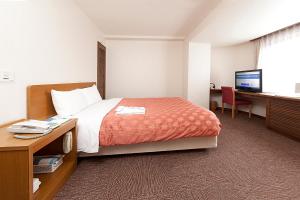 东村山市久米川翼酒店的酒店客房配有一张床、一张书桌和一台电脑