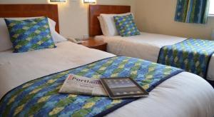 波特兰高地酒店的酒店客房,配有两张床,床上有一本书