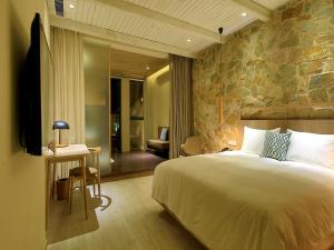 杭州EBO Hotel Zijin gang Asian Games Park Store Zhejiang university的一间卧室设有一张大床和石墙