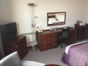 勒威克设德兰酒店的一间卧室配有书桌、一张床和镜子