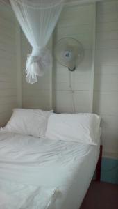 圣乔治Cosy Hut的一间卧室配有一张带白色床单的床和风扇