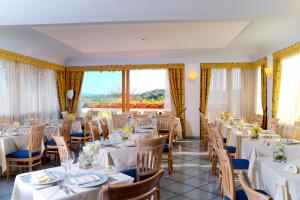 伊斯基亚贝尔维尤健身及放松酒店的一间设有白色桌椅和窗户的用餐室
