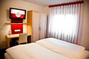 科斯费尔德斯特哈奴斯啤酒屋酒店的一间卧室配有一张床、一张书桌和一台电视