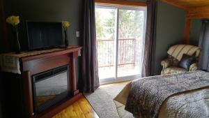 KingsclearStrong Timbers BnB的一间卧室设有壁炉、电视和床。