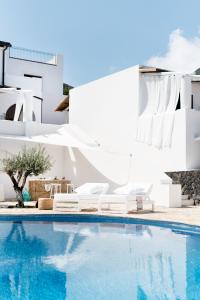 马尔法Principe Di Salina Boutique Hotel的一座房子旁的游泳池,配有两把白色椅子