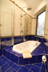 阿杰罗拉杜特丽酒店的蓝色瓷砖浴室设有浴缸和淋浴。