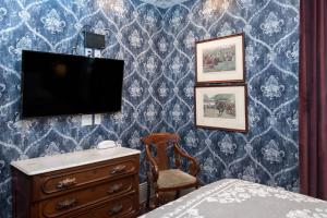 旧金山Monte Cristo Bed and Breakfast的一间卧室配有梳妆台和蓝色墙壁上的电视