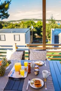 耶泽拉Adrijela Mobile Home的阳台上摆放着蓝色桌子,上面摆放着食物和饮料