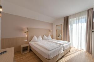 泰尔梅诺Tirolerin Garni Hotel的一间卧室设有一张大床和一个大窗户