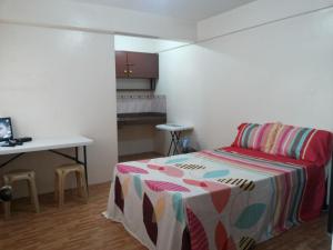 马尼拉马卡蒂经济一室公寓的一间卧室配有一张床、一张桌子和一张书桌