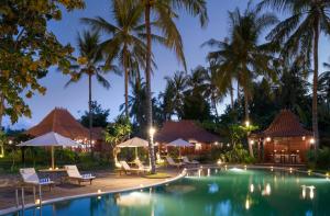 丹戎龙目岛钻石海滩别墅的夜间带椅子和棕榈树的度假游泳池