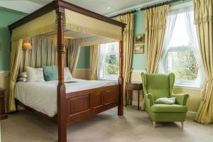 巴斯欧菲尔姿别墅酒店的一间卧室配有天蓬床和绿椅