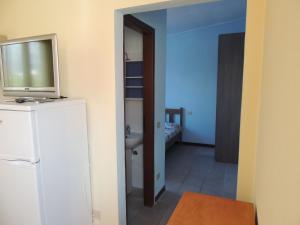 阿尔本加Appartamenti Camping Rivamare的浴室设有冰箱上方的电视