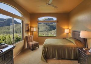 土桑Casitas at Sabino Springs的一间卧室配有一张床和一把椅子,还有两个窗户