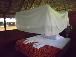 马尔多纳多港Ecolucerna Lodge Tambopata的一张带白色天蓬的床和两条毛巾