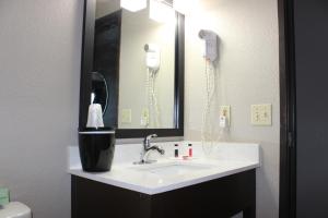 怀俄明Super 8 Grand Rapids City Center的一间带水槽和镜子的浴室以及一部电话