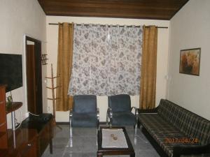 佩尼多Kitnet Penedo的客厅在窗户前配有沙发和椅子