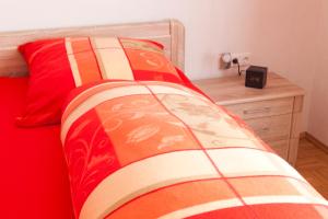Plankstadt科尔公寓的一张带红色棉被和木床头柜的床