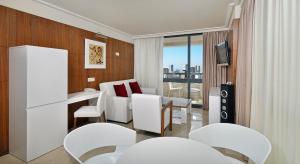 贝尼多姆贝尼多姆美利亚酒店的一间设有白色椅子、桌子和电视的房间