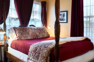 新奥尔良The Blue60 Marigny Inn的一间卧室配有一张带红色窗帘的天蓬床