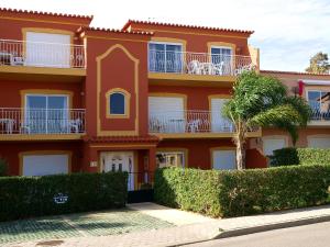 波尔蒂芒Apartment Palmeiras的一座红色的建筑,前面有棕榈树