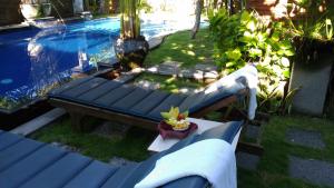 沙努尔巴厘巴厘岛普拉斯奇塔酒店的游泳池旁的蓝色长椅