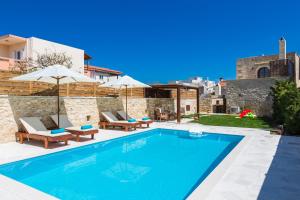 AngelianaAni Villa, authentic Cretan lifestyle的一座带椅子和遮阳伞的游泳池位于一座建筑旁边
