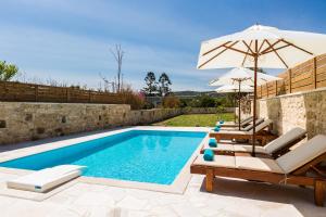 AngelianaAni Villa, authentic Cretan lifestyle的一个带椅子和遮阳伞的游泳池