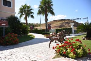 卡诺萨迪普利亚达塔微拉酒店的种有长椅和花卉的公园,棕榈树