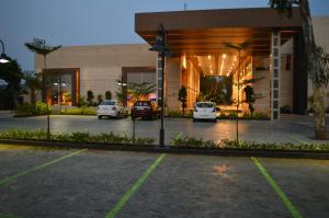 马哈巴利普拉姆Welcomhotel by ITC Hotels, Kences Palm Beach, Mamallapuram的停车场在一座有车停放的大楼前