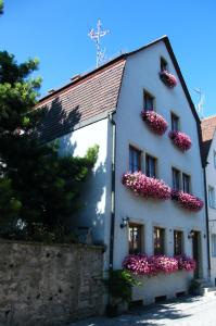 罗滕堡霍夫曼施默泽膳食公寓酒店的白色的建筑,旁边是粉红色的花朵