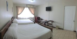 阿拉胡埃拉圣玛丽亚旅馆的一间卧室设有两张床和窗户。