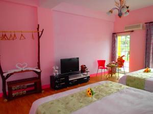 关山镇花田村民宿的粉红色的客房设有两张床和电视。
