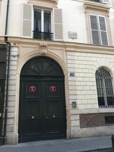 巴黎1er Etage SoPi-Montmartre的一座带两扇窗户的黑色门的建筑