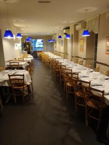 洛韦雷贝维德雷酒店的大型用餐室配有白色桌子和木椅