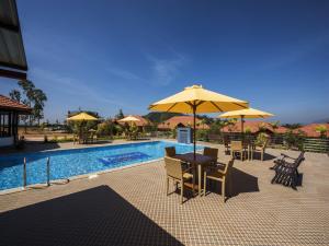 马迪凯里Woodstock Resorts的游泳池旁的天井配有桌子和遮阳伞