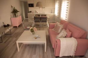 科尔多瓦Apartamento El Balcon de la Muralla的客厅配有粉红色的沙发和桌子