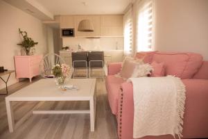 科尔多瓦Apartamento El Balcon de la Muralla的客厅配有粉红色的沙发和桌子