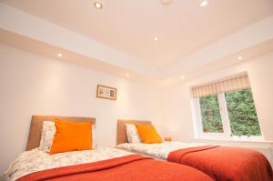 唐克斯特Warren House的卧室内的两张床和橙色枕头