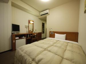 佐贺市佐贺站前干线酒店的一间卧室配有一张床、一张书桌和一台电视