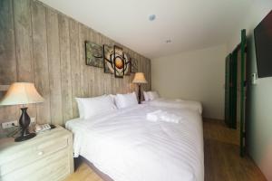 坤敬Anchan Laguna Hotel โรงแรมอัญชันลากูน่า的卧室配有一张白色大床和两盏灯。