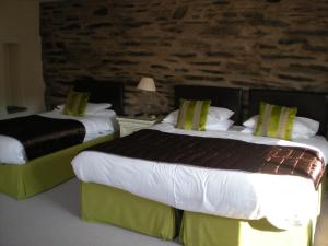 科尼斯顿黑公牛酒店的酒店客房设有两张床和石墙。