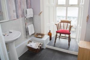 卡纳芬安格尔西纹章酒店的一间带椅子、水槽和窗户的浴室