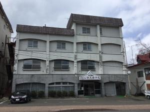 阿寒湖畔松冈商务经济型酒店的前面有停车位的建筑
