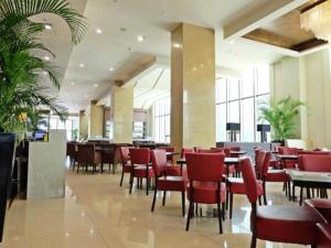 宿务曼德闰普拉扎酒店的餐厅设有红色的椅子和桌子以及窗户。