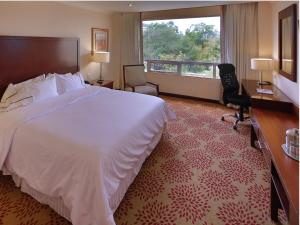 危地马拉比尔特莫酒店的配有一张床、一张书桌和一扇窗户的酒店客房