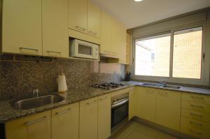 滨海托萨Lets Holidays Apartment Vinya del Pla的厨房配有黄色橱柜、水槽和微波炉