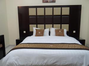 代瓦西尔干河Royal Home Furnished Apartments的一间卧室配有一张大床和黑色床头板