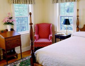 EssexThe Griswold Inn的一间卧室配有一张床、一把椅子和窗户。
