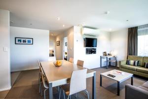 奥克兰奎斯特奥尔巴尼服务式公寓的用餐室以及带桌椅的起居室。